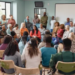 An image of a diverse group of individuals gathered in a community center, engaged in a diabetes support group meeting, where they are sharing their experiences, offering advice, and providing emotional support to one another.