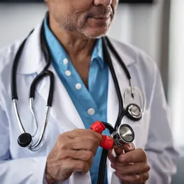 A close-up image of a doctor holding a stethoscope to a patient's chest, highlighting the connection between heart health and blood sugar levels.